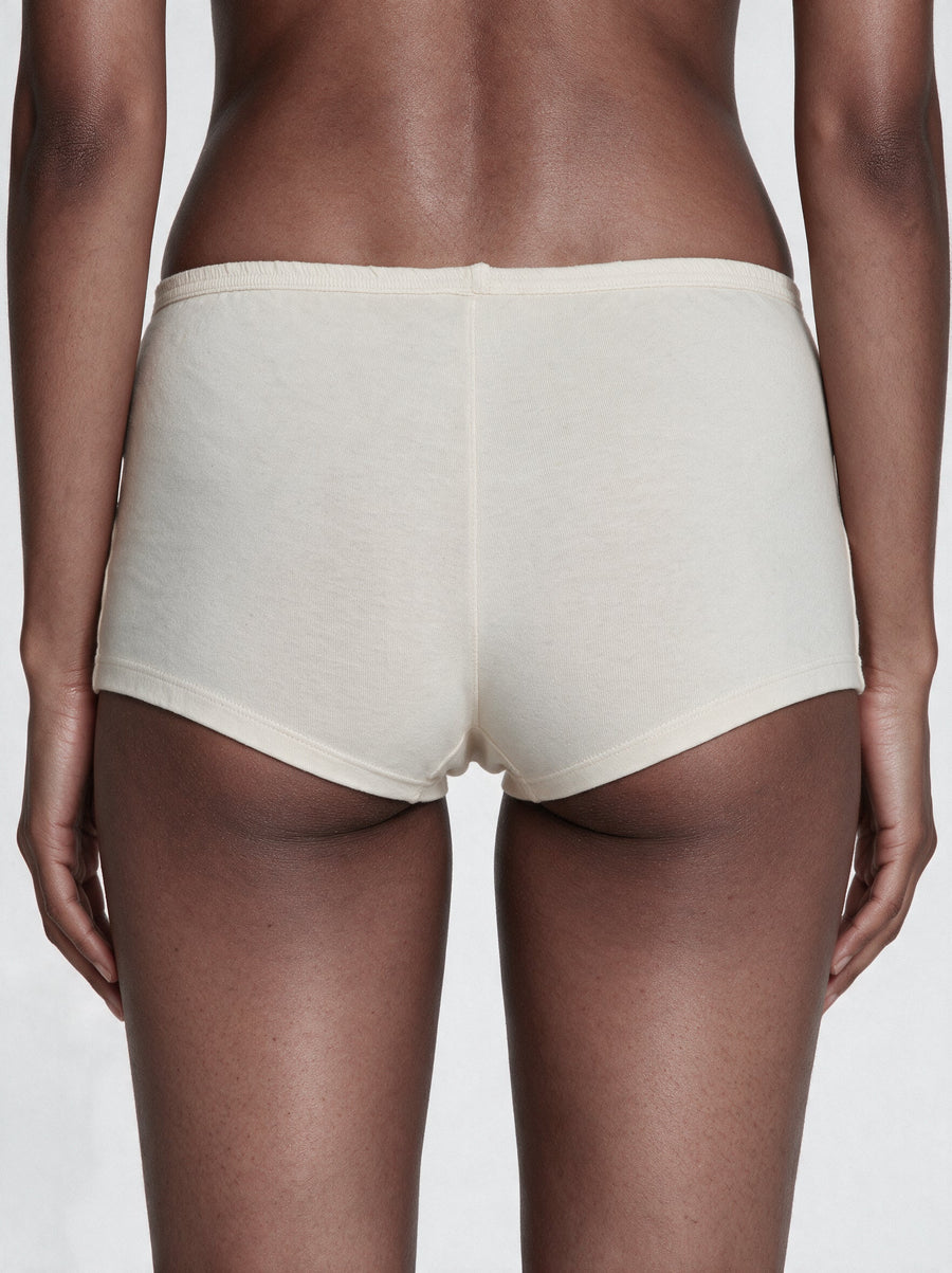 Flat-lay of undyed organic cotton boy shorts for women on a soft neutral background
